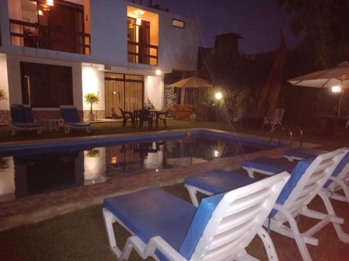 a group of chairs sitting next to a swimming pool at night at Montemar Apart Hotel - Playa Huanchaco in Huanchaco