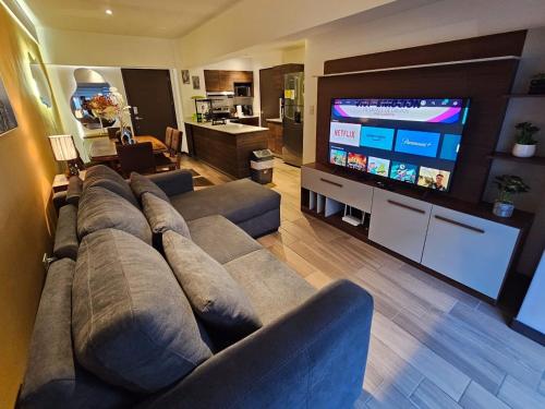 sala de estar con sofá grande y TV de pantalla plana en Torre Pamplona 102-Nuevo y Céntrico-Apartamento en Guatemala