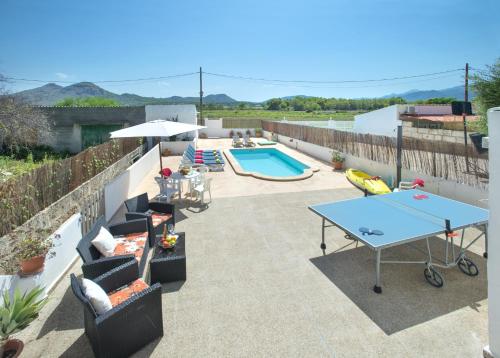 eine Terrasse mit einer Tischtennisplatte und einem Pool in der Unterkunft Owl Booking Villa Trinxater - 12 Min Walk to the Beach in Alcúdia