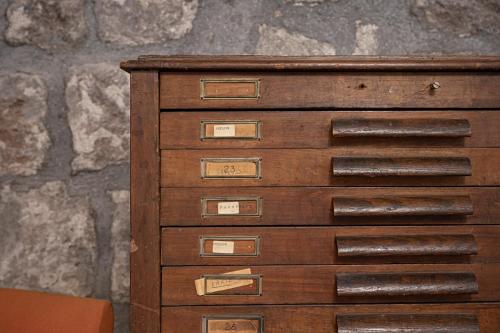 a wooden dresser with nine drawers and a stone wall at Inter Artes Prestige House and Luxury Suite in Viterbo