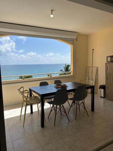 a dining room with a table and chairs and the ocean at L’Appart - Les pieds dans l’eau in Sainte-Luce