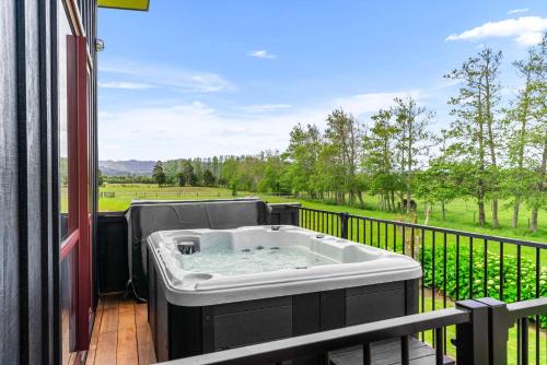 a hot tub on a balcony with a view at Summer Haze - Omaha Holiday Home in Matakana