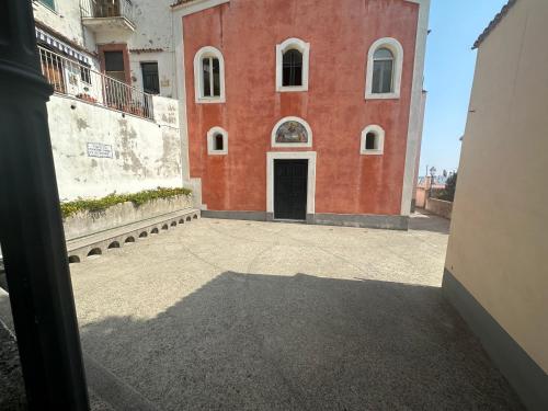 a red building with a black door in a courtyard at Ravello suite in Ravello