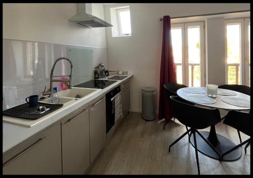 une cuisine avec un évier et une table avec des chaises dans l'établissement Le Cocon, à Saint-Quentin