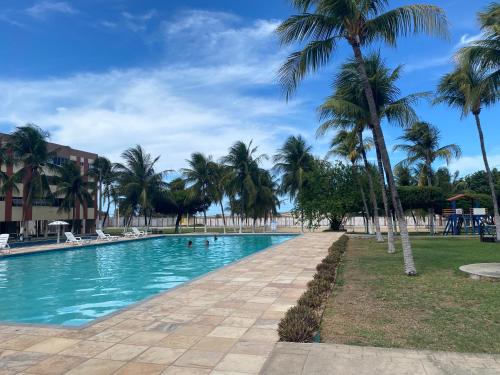 a swimming pool with palm trees in a resort at Apartamento térreo no Morro Branco Marina II in Beberibe