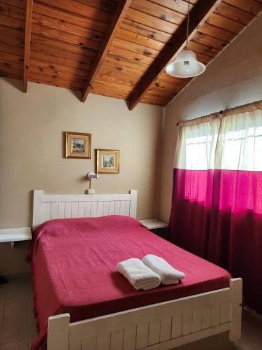 1 dormitorio con 1 cama roja y 2 toallas en Complejo Mayu Inti Wayra - Mayu Sumaj en Villa Icho Cruz