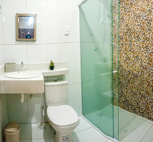 a bathroom with a toilet and a glass shower at Pousada Brumar in Maragogi