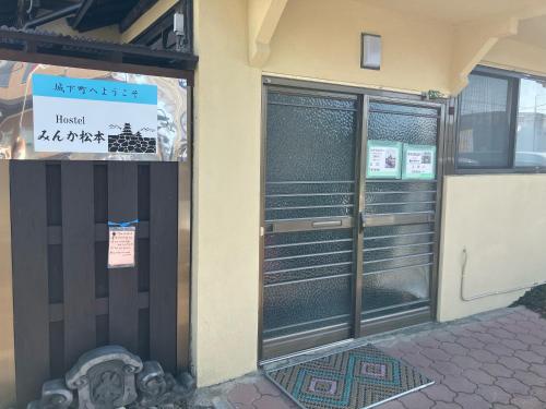una puerta delantera de un edificio con un cartel en Hostel みんか松本 en Matsumoto