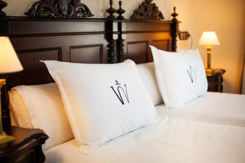 a bed with white pillows and a wooden headboard at Hotel Palacio de Hemingway in Ronda