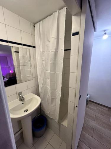 une salle de bain blanche avec un lavabo et un miroir dans l'établissement Studio charmant centre Idéal, à Paris
