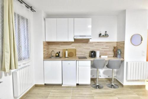 a white kitchen with white cabinets and two stools at Magic Spa Studio Jacuzzi near Disneyland in Crecy la Chapelle