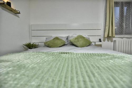 a white bed with two green pillows on it at Magic Spa Studio Jacuzzi near Disneyland in Crecy la Chapelle