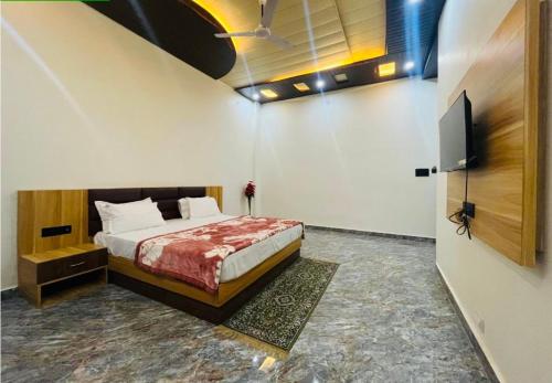 a bedroom with a bed and a flat screen tv at Lotus Palm Retreat - Full Villa (By A.P. Villa's) in Ujjain