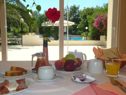 una mesa con platos de comida y un jarrón con rosas en Monte Vardia, en La Canea