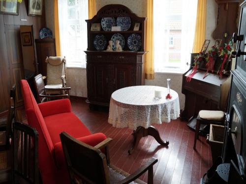 a living room with a table and red chairs at Gasthuus Ulenhoff in Westoverledingen