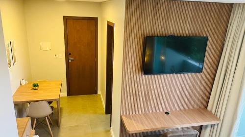 a room with a television on a wall with a table at Suítes Costa Do Macacu-Garopaba in Garopaba