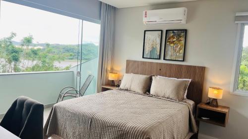 a bedroom with a bed and a large window at Suítes Costa Do Macacu-Garopaba in Garopaba