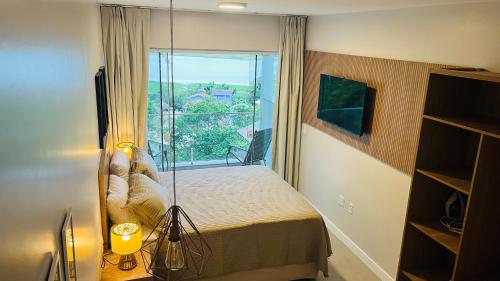 um quarto com uma cama e uma grande janela em Suítes Costa Do Macacu-Garopaba em Garopaba
