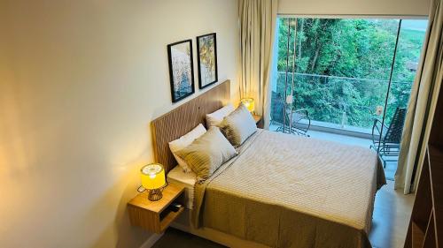a bedroom with a bed and a window with a view at Suítes Costa Do Macacu-Garopaba in Garopaba