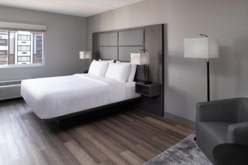 a bedroom with a large white bed and a chair at TownePlace Suites by Marriott Framingham in Framingham