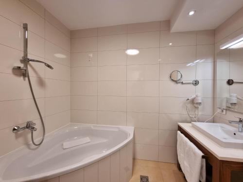 a white bathroom with a tub and a sink at Apartman Queen Vučko in Jahorina