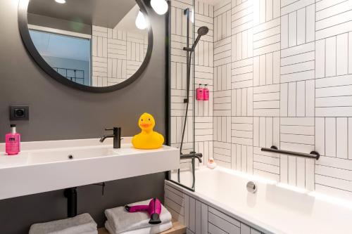 ein Bad mit einem Waschbecken und einem Spiegel in der Unterkunft Moxy Bordeaux in Bordeaux