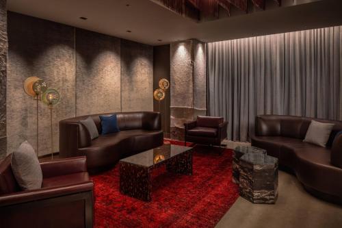 a living room with leather furniture and a red rug at The Joseph, a Luxury Collection Hotel, Nashville in Nashville