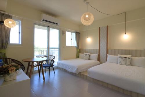 a hotel room with two beds and a table with a table at 花蓮雲朵朵民宿 電梯附停車場 in Jian