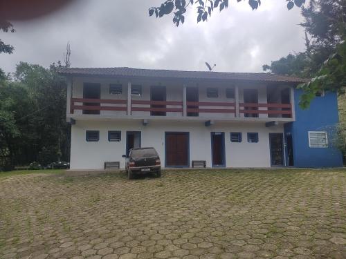 una casa azul y blanca con un coche aparcado delante en Pousada Uai, en Alagoa