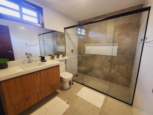 uma casa de banho com um chuveiro, um lavatório e um WC. em GP05 - Chalé em pousada a 300m da Praia do Amor em Pipa