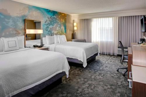 a hotel room with two beds and a desk at Courtyard Cleveland Airport South in Middleburg Heights