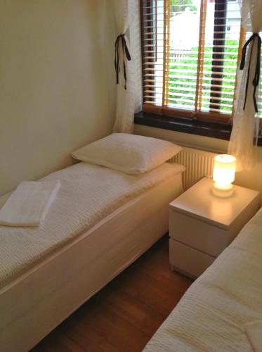 two beds in a room with a lamp on a table at Sólheimar Apartment in Húsavík