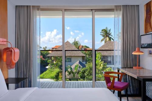 a hotel room with a bed and a large window at Aloft Bali Seminyak in Seminyak
