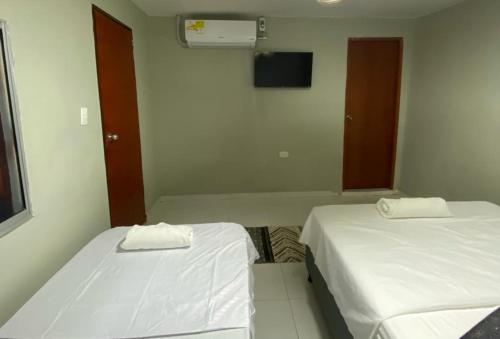 een kamer met 2 bedden en een tv aan de muur bij HOSTAL CASA PALMA in Ríohacha