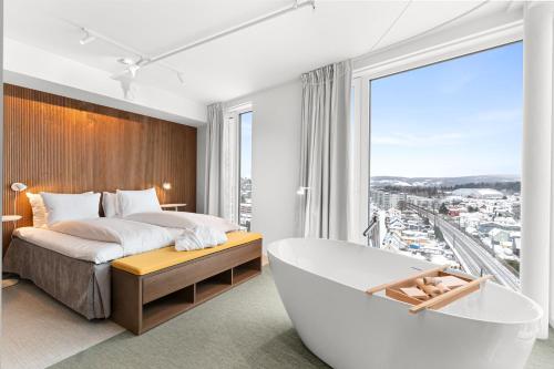 a bedroom with a tub and a large window at LUX Hotel in Lillestrøm