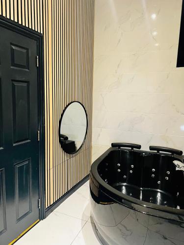 a black tub in a bathroom with a mirror at Duke and Duchess Apartments and Rooms - Private in Room Hot Tub Suites in London