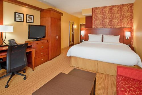 a hotel room with a bed and a desk and a television at Courtyard by Marriott Pittsburgh North/Cranberry Woods in Cranberry Township