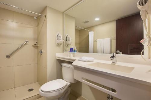 uma casa de banho com um WC, um lavatório e um chuveiro em City Express by Marriott San José Costa Rica em San José