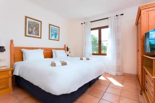 ein Schlafzimmer mit einem großen Bett und einem TV in der Unterkunft Marriott’s Club Son Antem in Llucmajor