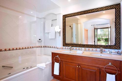 een badkamer met een bad, een wastafel en een spiegel bij Marriott’s Club Son Antem in Llucmajor