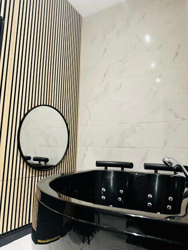 a black tub in a bathroom with a mirror at Duke and Duchess Apartments and Rooms - Private in Room Hot Tub Suites in London