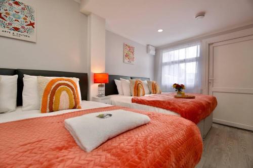 a bedroom with two beds with orange sheets and a window at Dane Studio 13 – Coventry in Coventry
