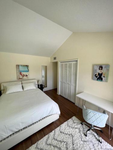 a bedroom with a large white bed and a desk at SWISS 24 - Lake Stephanie in Clermont