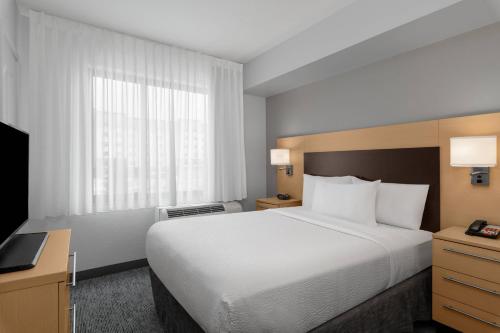 a hotel room with a large bed and a television at TownPlaces Suite Denver Airport at Gateway Park in Aurora