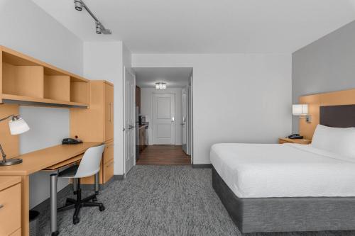 a hotel room with a bed and a desk and a bedroom at TownPlaces Suite Denver Airport at Gateway Park in Aurora