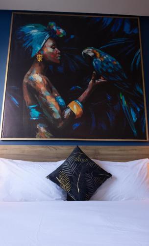 a painting of a woman with a bird on a bed at Playa Del Sol Surf House in Tamraght Ouzdar