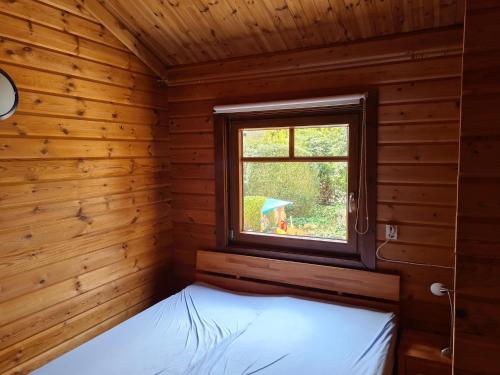 a room with a bed in a wooden room with a window at Ferienhaus-Kaninchenhoehle in Haren