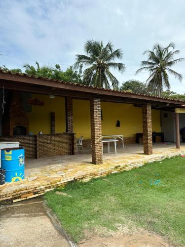 uma casa com um pátio com uma mesa e palmeiras em Brisa da lagoa em Paracuru