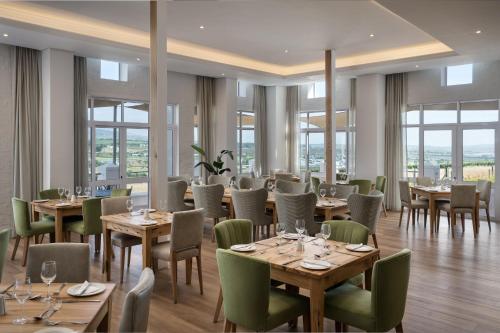 a restaurant with wooden tables and chairs and windows at Protea Hotel by Marriott Stellenbosch & Conference Centre in Stellenbosch