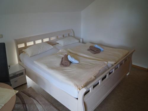 a white bed with two pairs of shoes on it at Gasthuus Ulenhoff in Westoverledingen